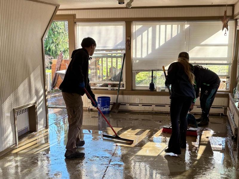 Coaches and players clean up a flooded house.