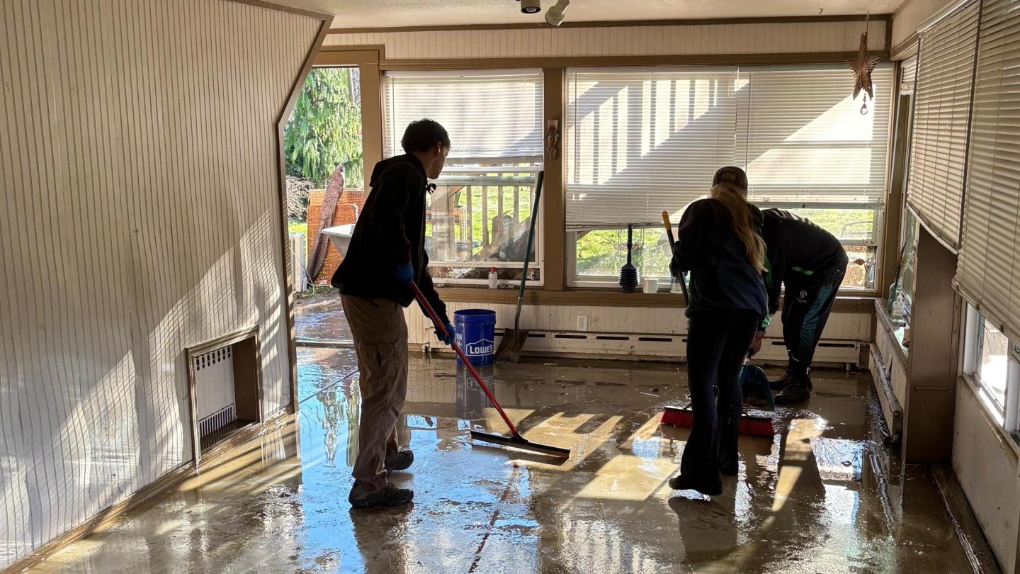 Coaches and players clean up a flooded house.