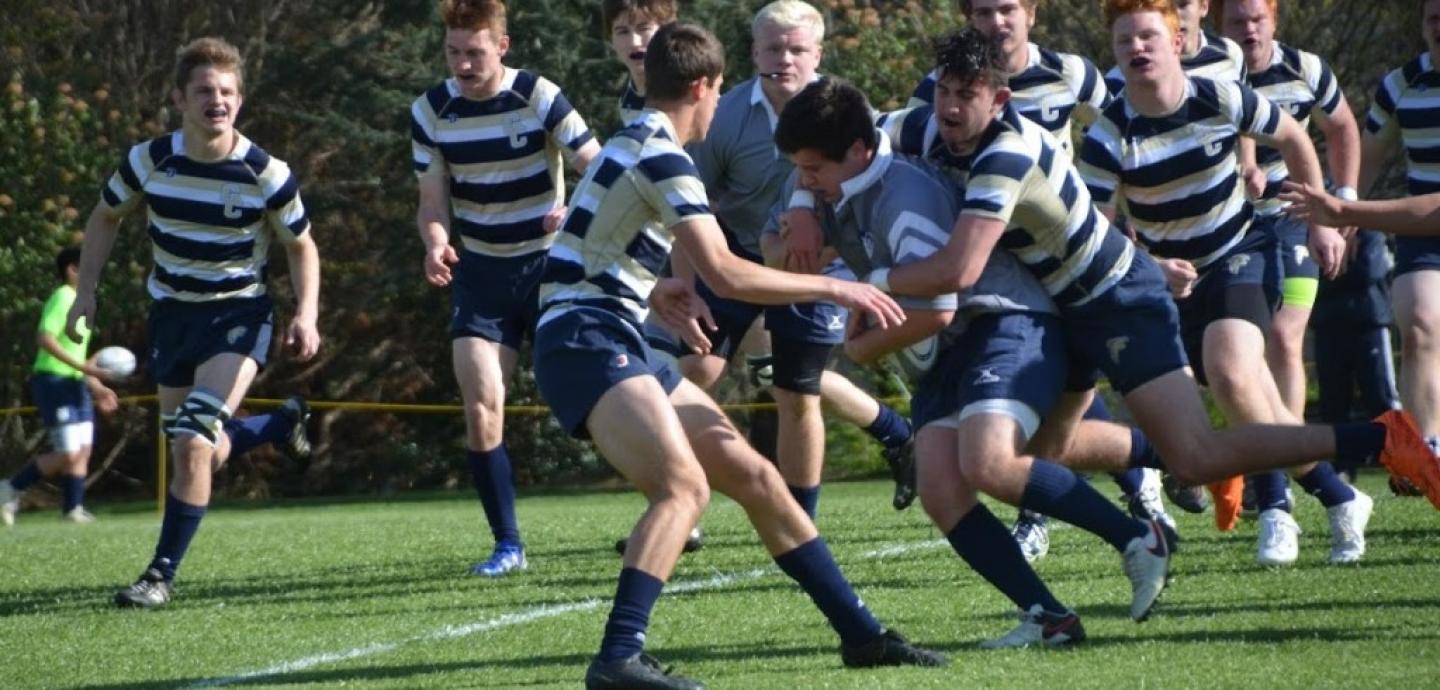 prop reily barlett carries the ball and a gc defender for prep
